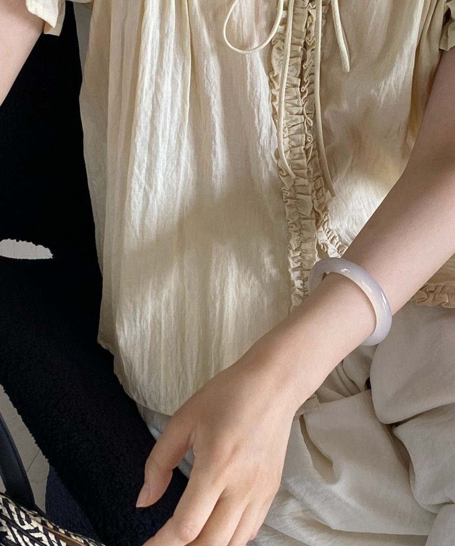 イエローのフリルブラウスのフリルとリボンのディテールにフォーカスした画像。