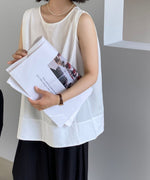 ホワイトブラウスを着た女性が手に新聞を持っている。