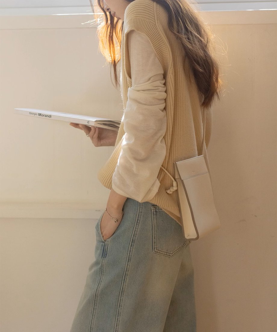 ベージュのニットベストを着用した女性の横からのスタイル。