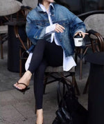 デニムジャケットと白シャツをコーディネートした女性が椅子に座っている写真