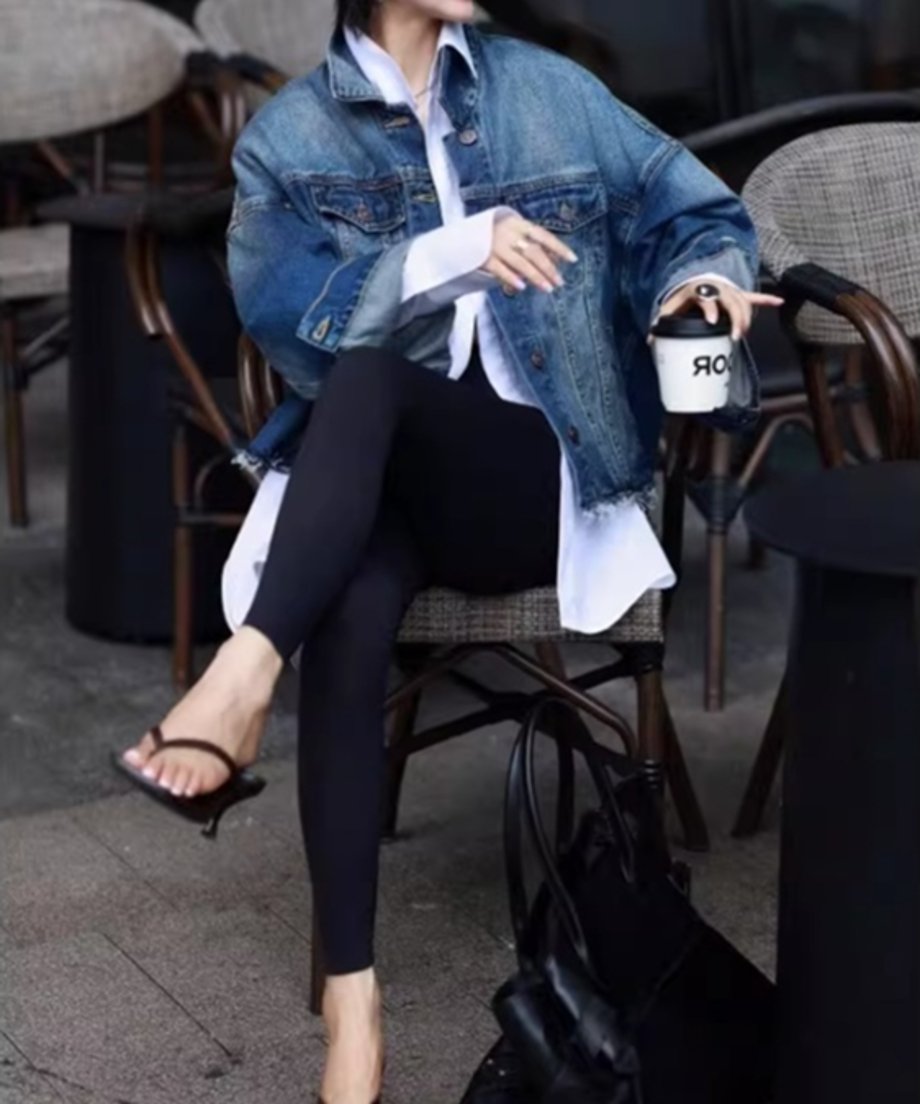 デニムジャケットと白シャツをコーディネートした女性が椅子に座っている写真