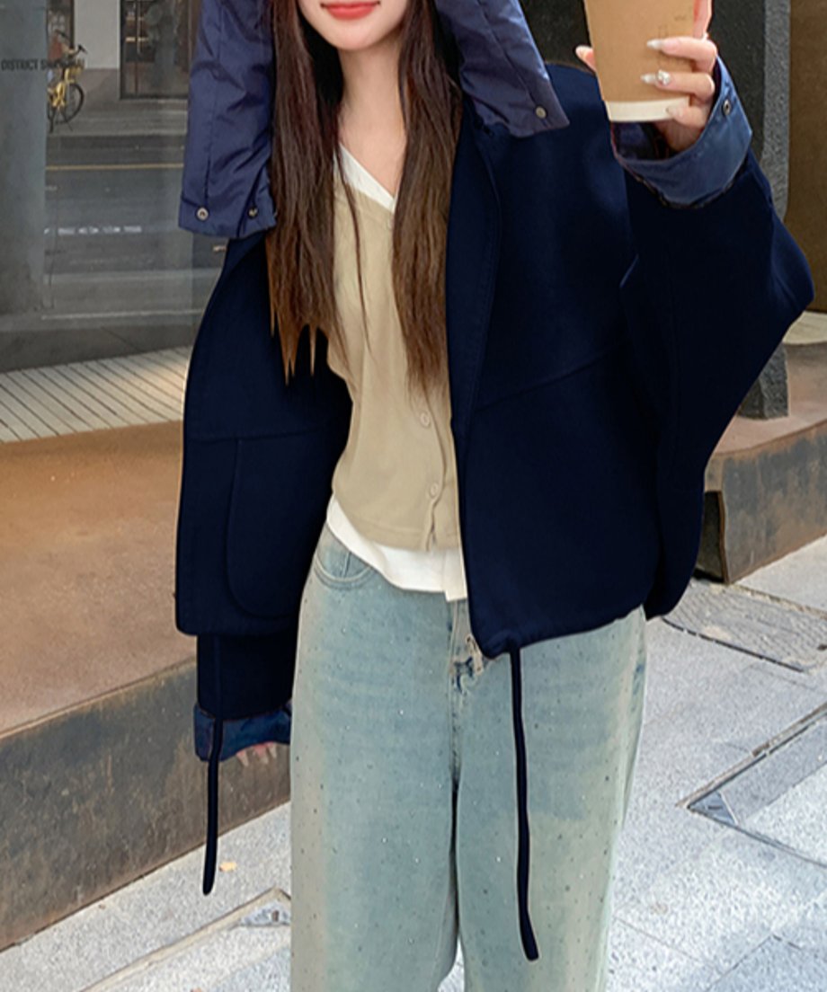 ネイビーのオーバーサイズジャケットを着た女性がをスマホを持っている様子。袖口のボタンディテールが見える。