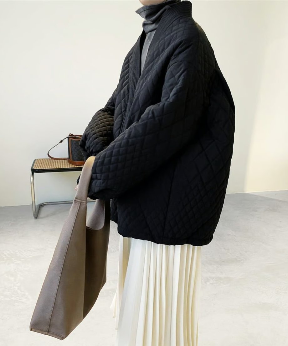 黒のキルティングオーバーサイズコートを着用した女性の横からの写真
