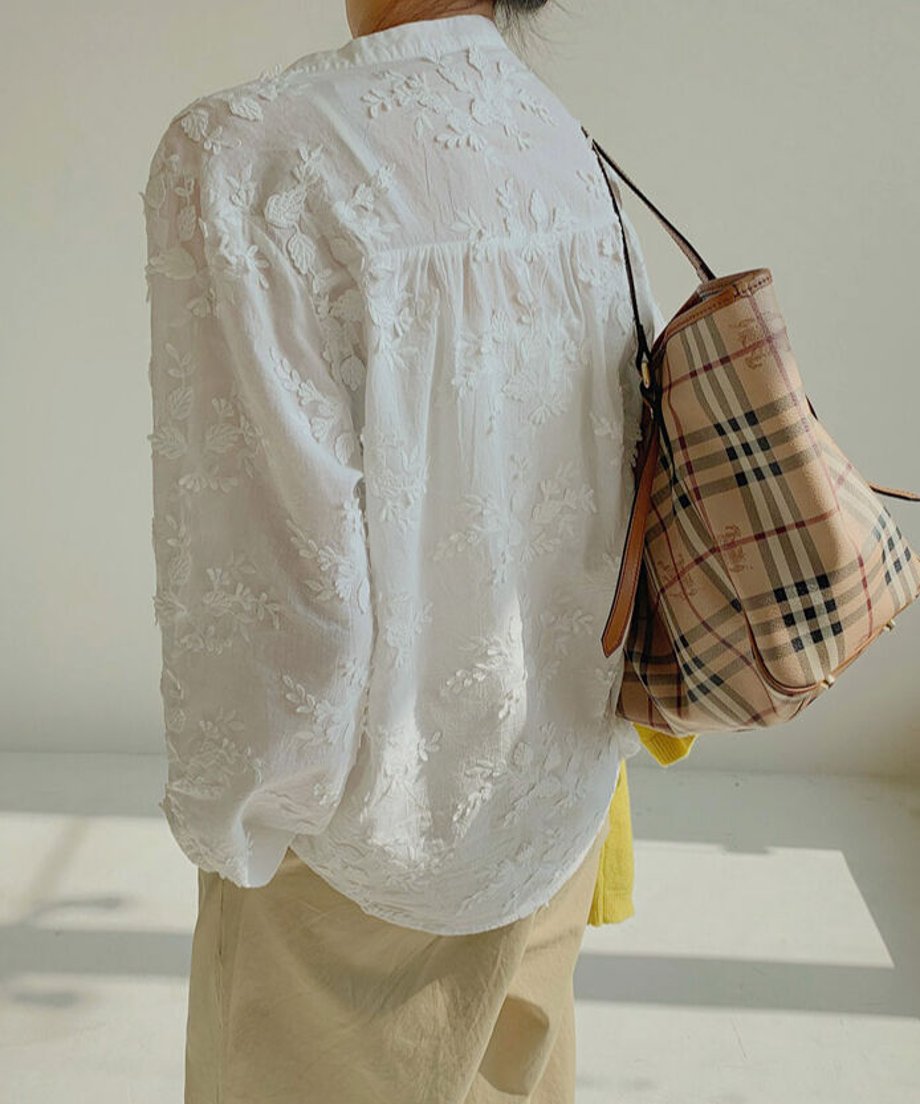 白いレース刺繍ブラウスを着た女性の後ろ姿とチェック柄のバッグ。
