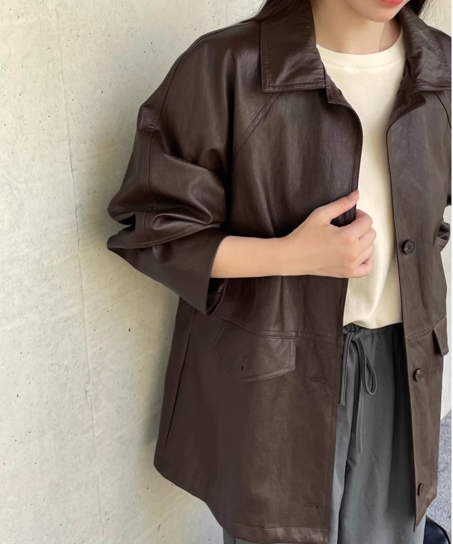 ダークブラウンのジャケットを着た女性が立っている画像。