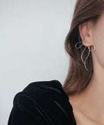 黒いトップスを着用した女性が、耳にゴールドのリボン型ピアスを付けている様子。