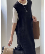 黒のロング丈透かし編みニットベストに白の半袖Tシャツを重ね着した女性の上半身。シルバーのネックレスを着用し、茶色のバッグを持っている。