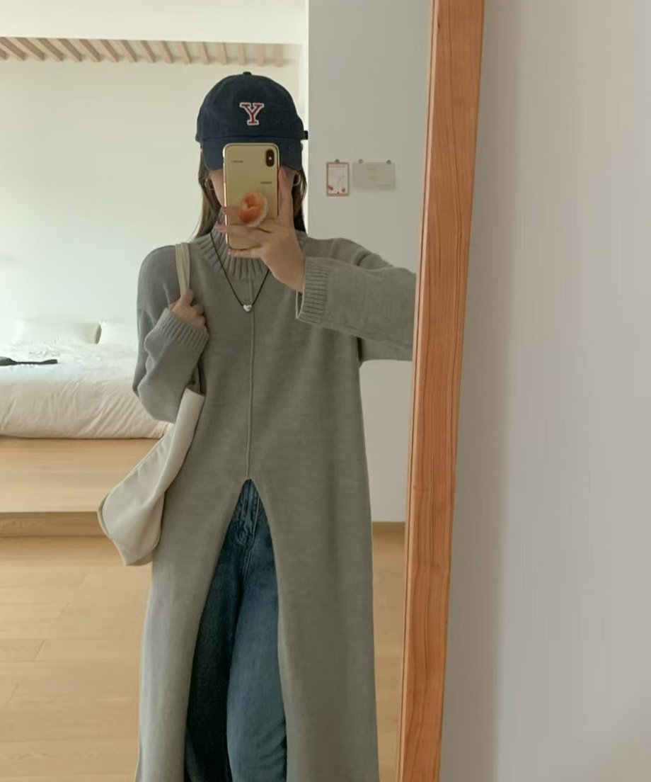 ライトグレーのタートルネックロングニットを着用した女性が、青いワイドデニムパンツをレイヤードした写真