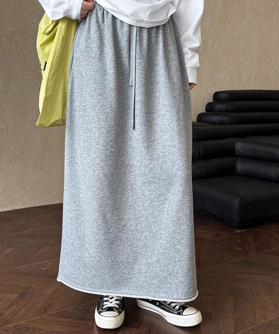 杢グレーのスウェット素材のロングスカートとスニーカーをコーディネートした女性。