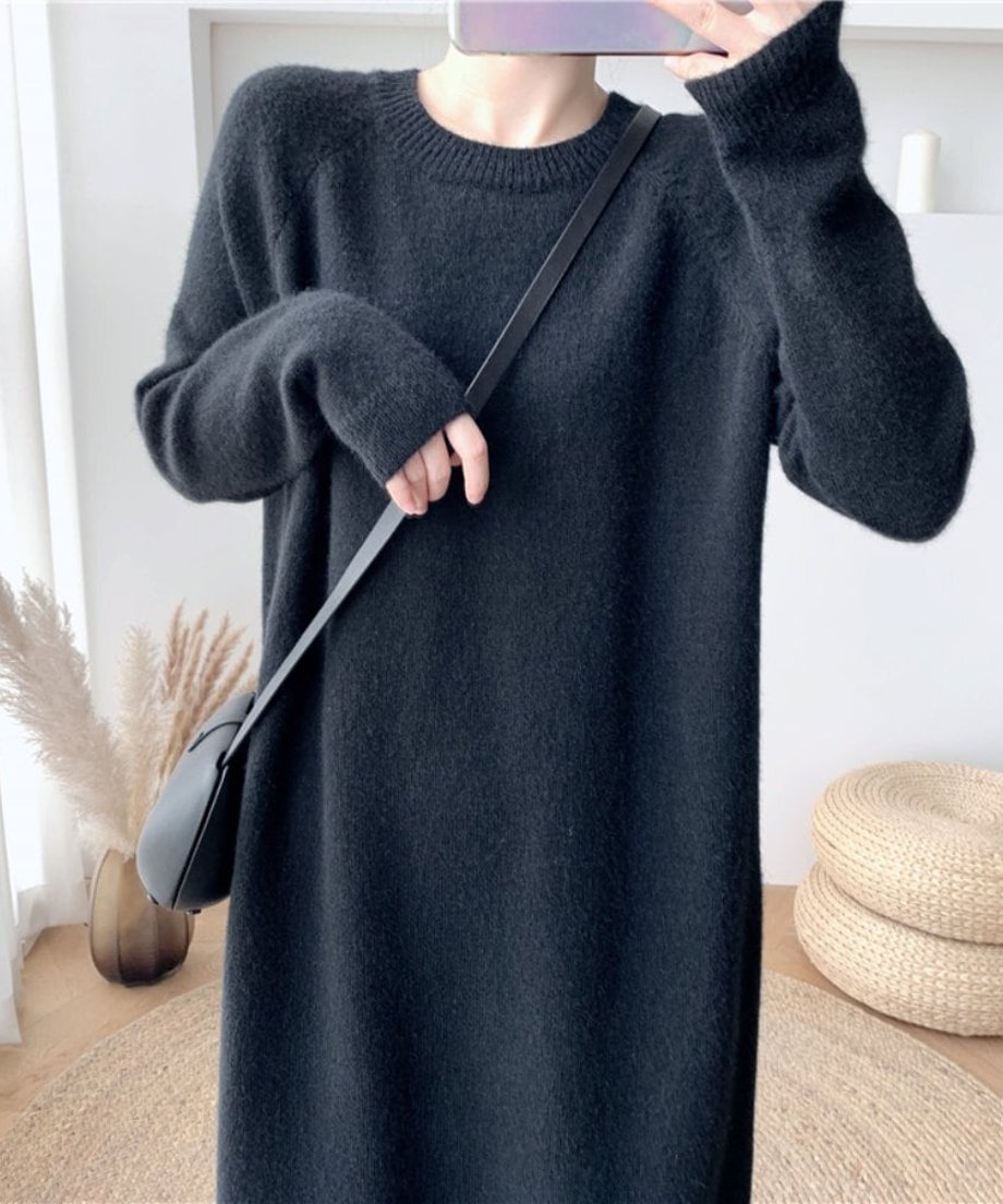 黒い長袖ニットワンピースを着用し、黒いショルダーバッグをかけた女性の胸元から腕にかけてのアップ。