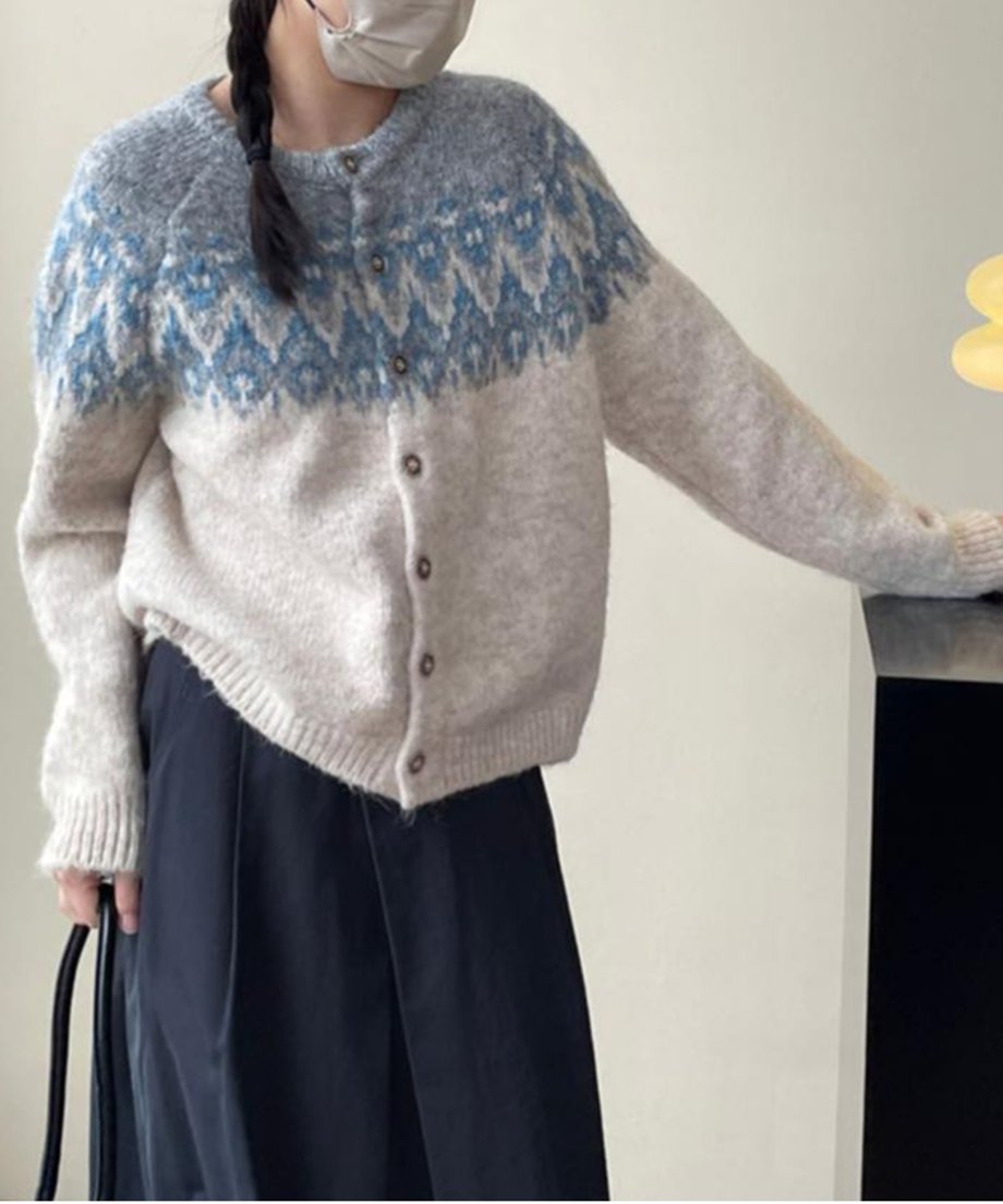 グレーをベースにブルーのフェアアイル柄が入った長袖ニットプルオーバーをワイドパンツとコーディネートしている女性。