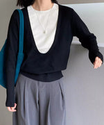 ブラックのディープUネックニットを着用した女性の半身像。白いTシャツをインナーに重ね、グレーのワイドパンツを着用。袖口のリブ編みが強調されている。
