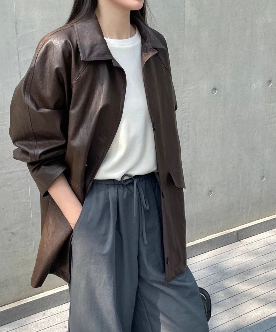 ダークブラウンのジャケットを着た女性がポケットに手を入れてポーズを決めている画像。