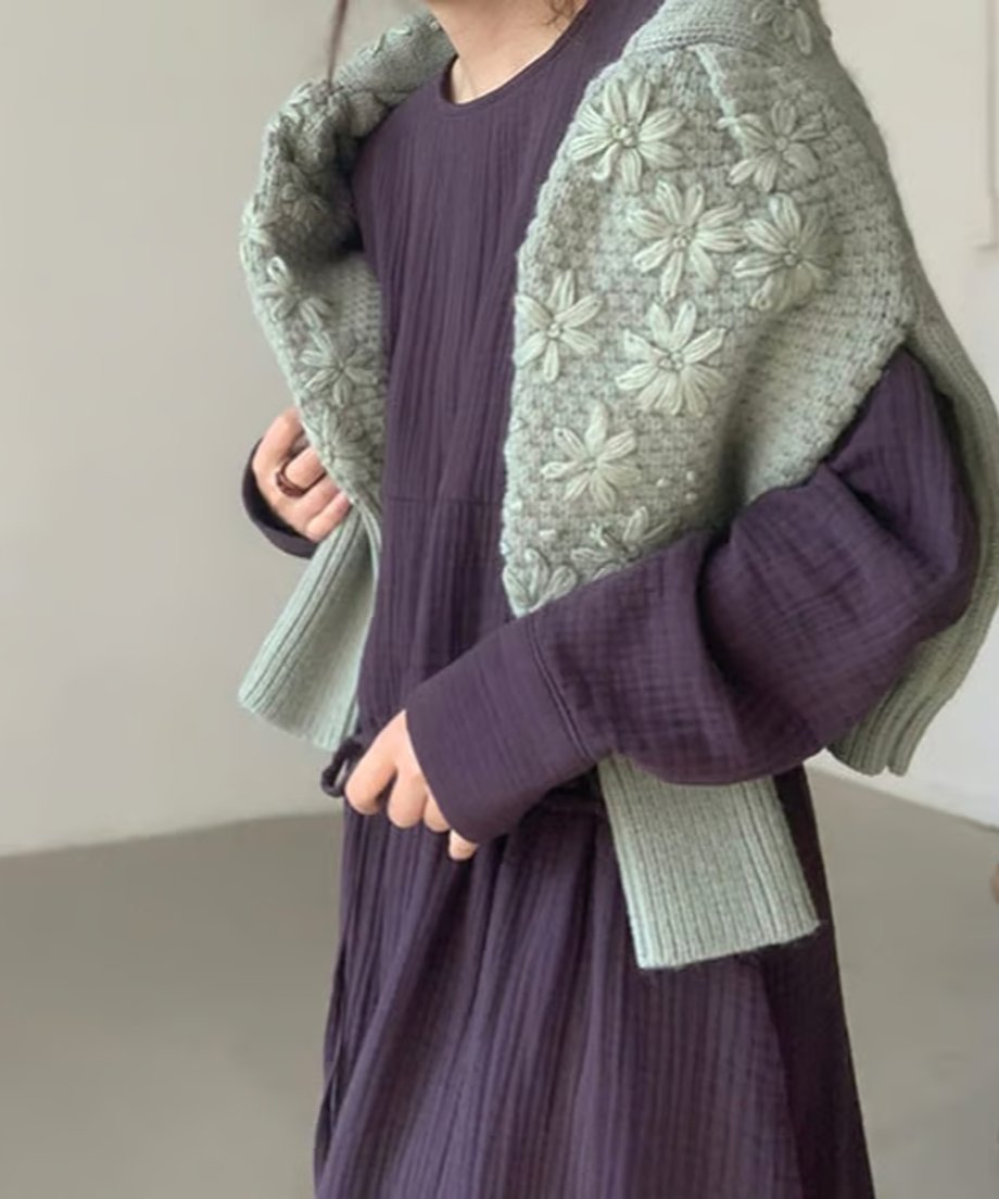 グリーンのフローラル刺繍セーターを肩にかけた女性、パープルのワンピースとコーディネート。