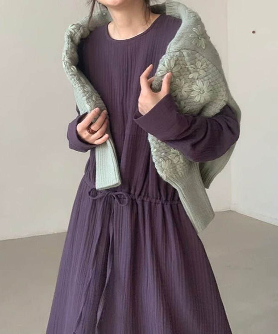 パープルのワンピースにグリーンのフローラル刺繍セーターを肩にかけた女性のコーディネート。