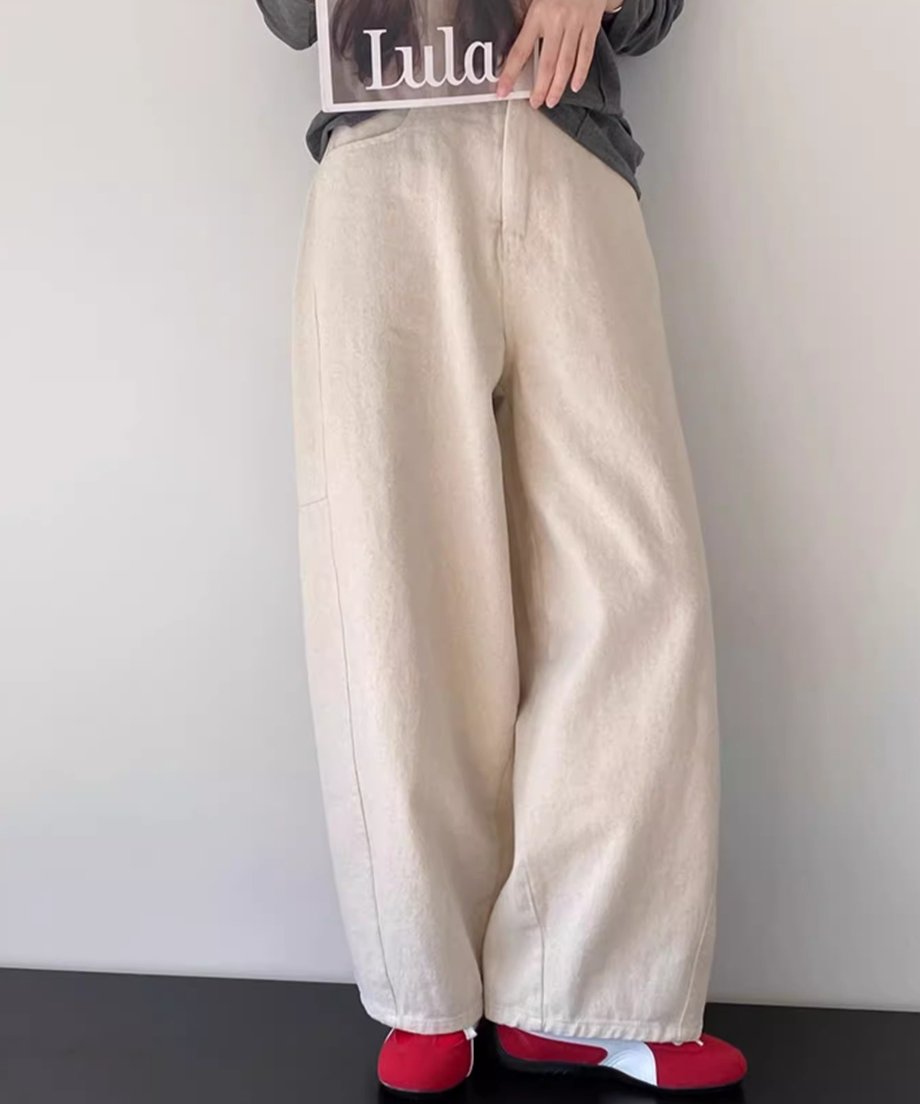 アイボリーのワイドパンツとチャコールグレーの長袖Tシャツを着た女性が座って雑誌を持っているクローズアップ写真。