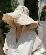 ベージュのリネンドレスワンピースに麦わら帽子を合わせた女性、夏らしい涼しげなスタイル