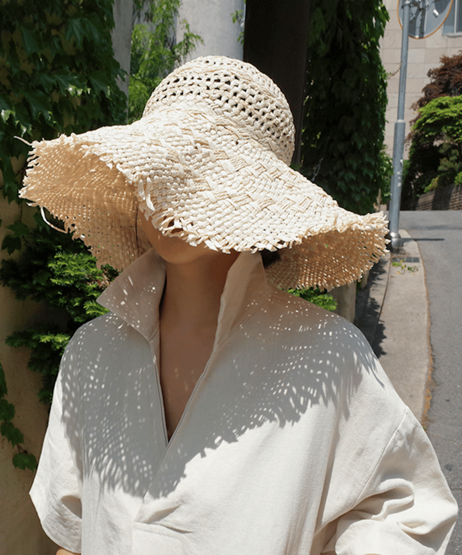 ベージュのリネンドレスワンピースに麦わら帽子を合わせた女性、夏らしい涼しげなスタイル