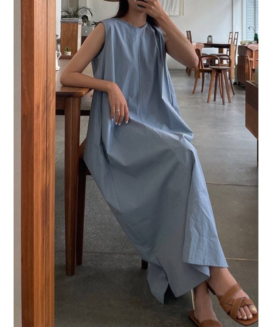 ライトブルーのノースリーブマキシワンピースを着てカフェの椅子に座る女性の正面。