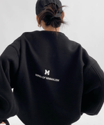 黒のオーバーサイズスウェットを着用した女性の後ろからのショット。背中の英字プリントが見える。