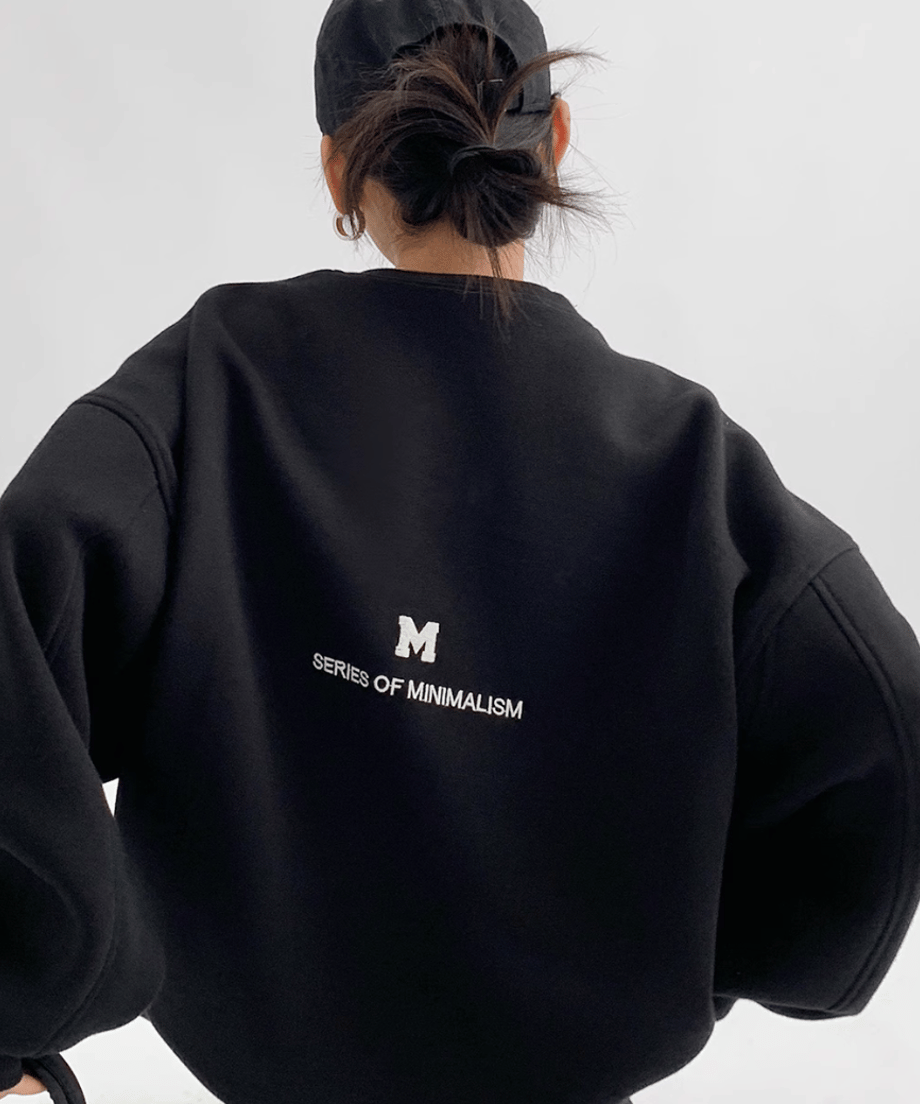 黒のオーバーサイズスウェットを着用した女性の後ろからのショット。背中の英字プリントが見える。