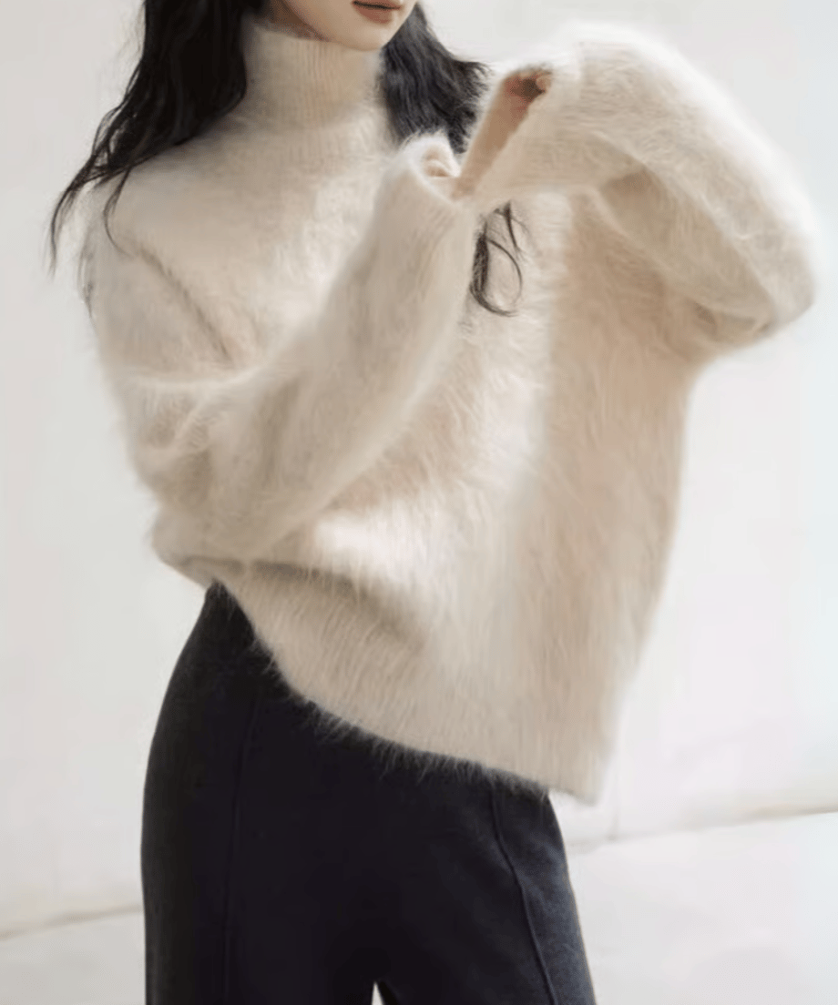 アプリコットの毛足の長いニットと、黒っぽいストレートワイドパンツを合わせた女性の写真。