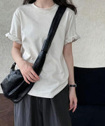 ベージュのTシャツと黒のショルダーバッグを合わせたシンプルな着こなし