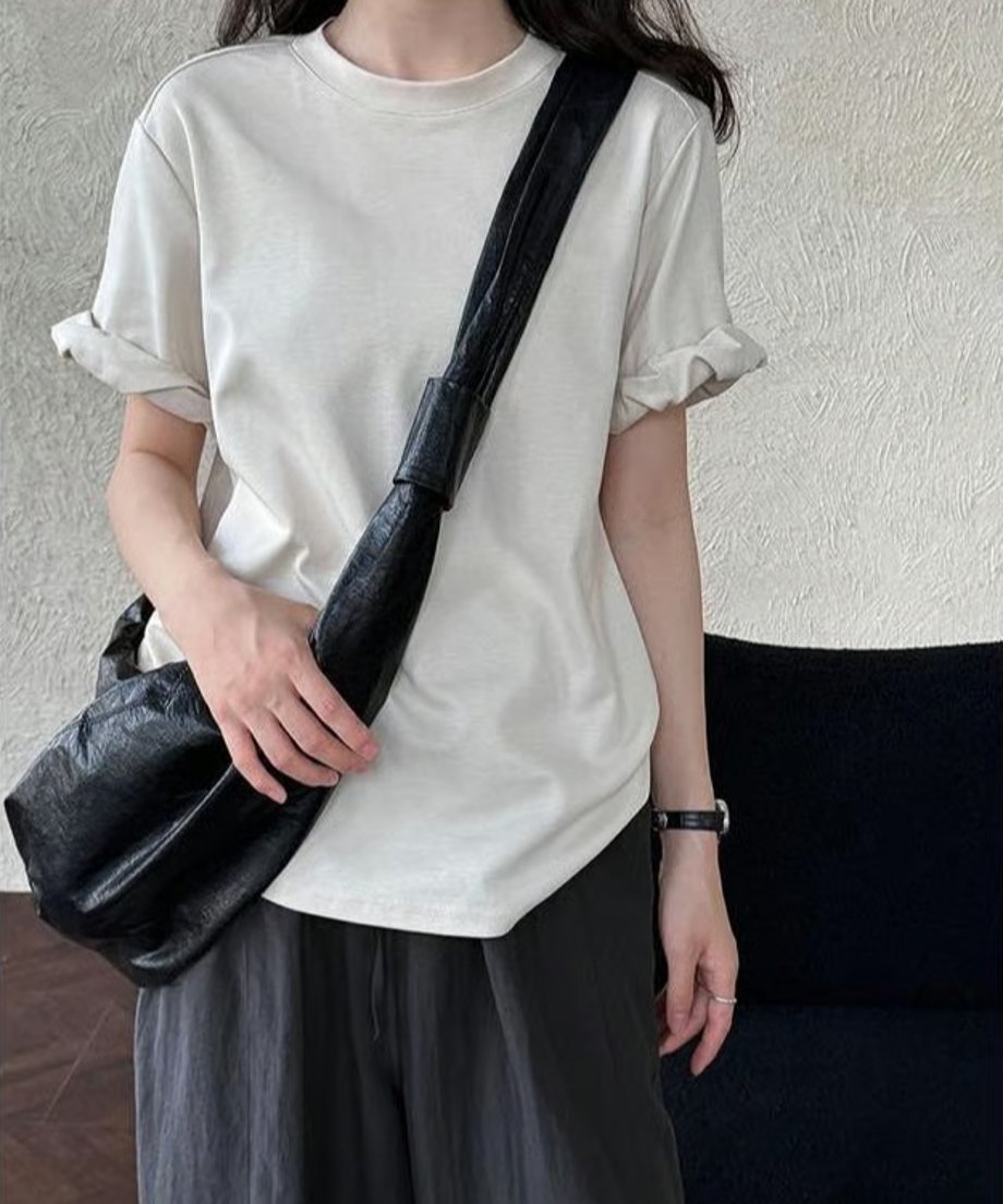 ベージュのTシャツと黒のショルダーバッグを合わせたシンプルな着こなし