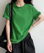 グリーンのTシャツを着た女性が黒いスカートとバッグを合わせたカジュアルコーディネート