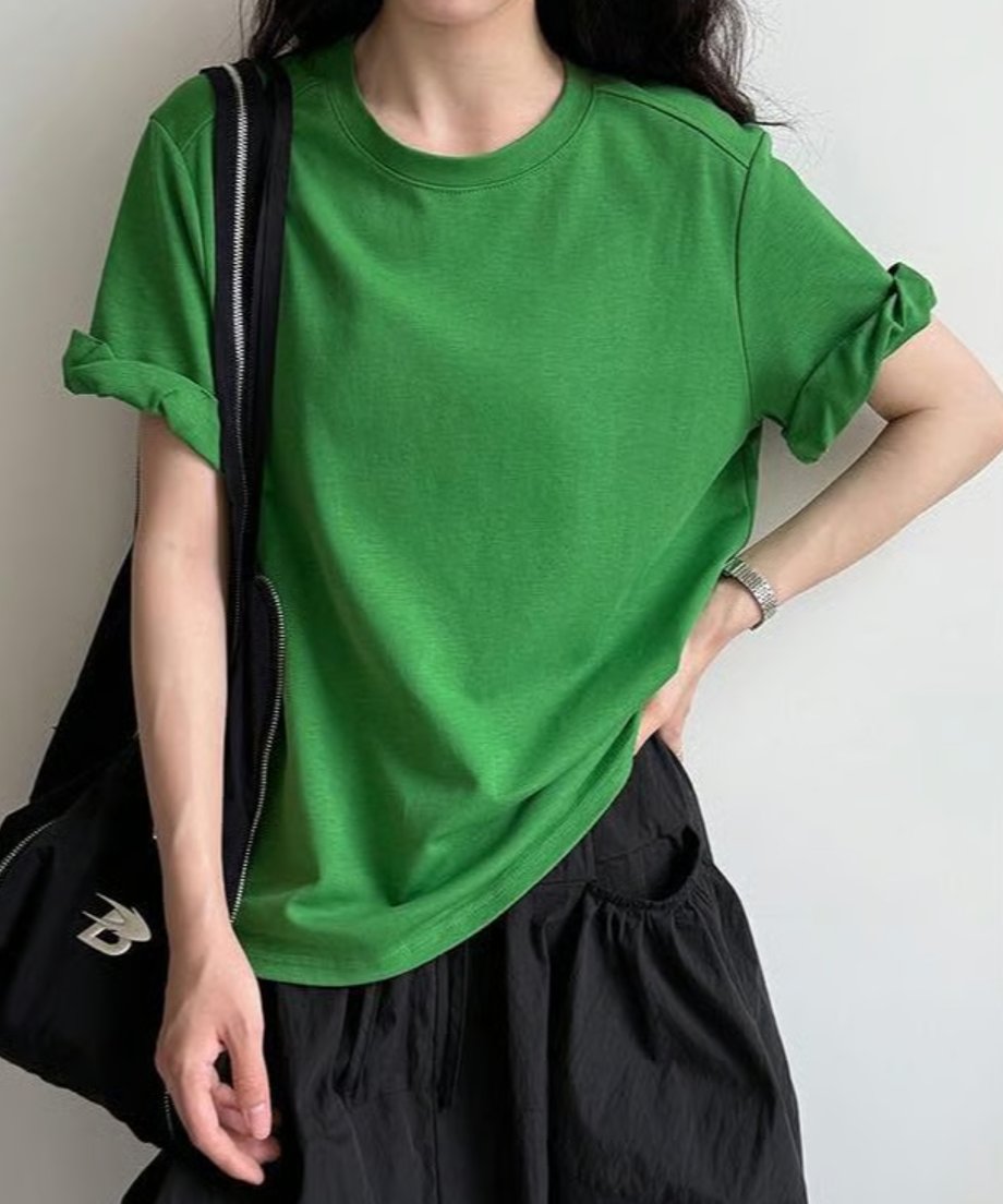 グリーンのTシャツを着た女性が黒いスカートとバッグを合わせたカジュアルコーディネート
