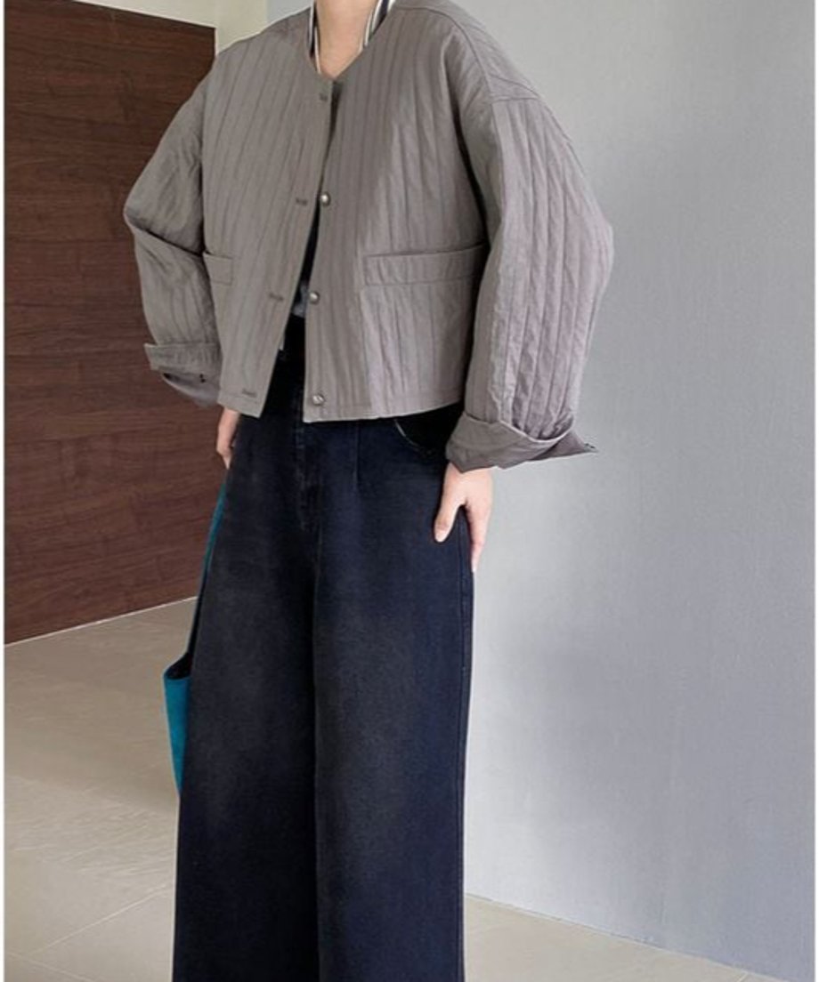 グレーのバルーンスリーブジャケットを着用した女性の全身。ジャケットはショート丈で、濃い色のワイドデニムパンツ、白いボーダーインナー、青いトートバッグを合わせたコーディネート。