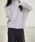 パープルの毛足の長いニットを着用した女性のバストアップ。