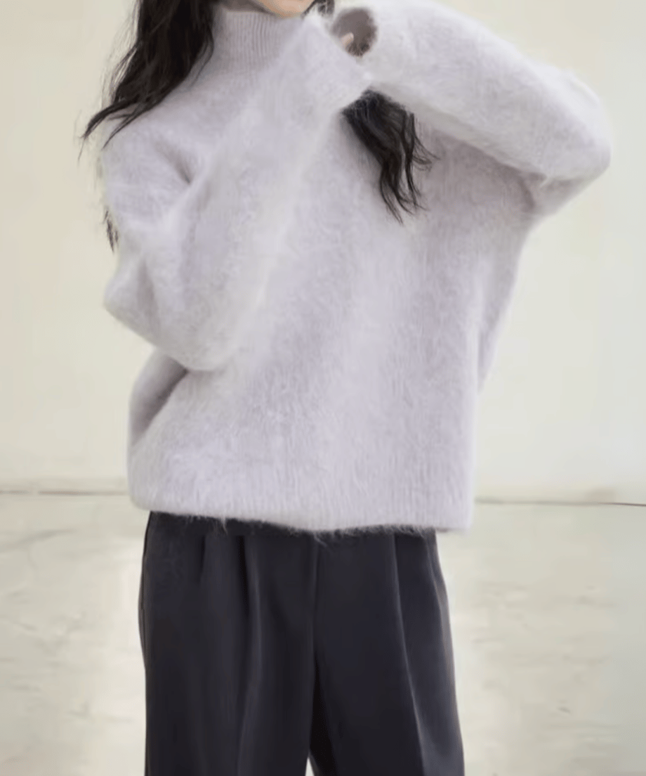 パープルの毛足の長いニットを着用した女性のバストアップ。