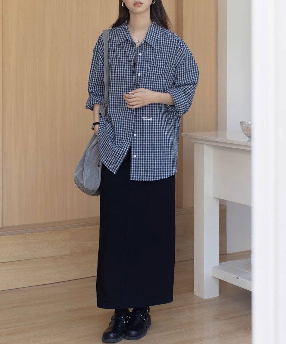 チェック柄シャツとブラックのマキシスカートを着た女性。オーバーサイズシャツのコーディネート。