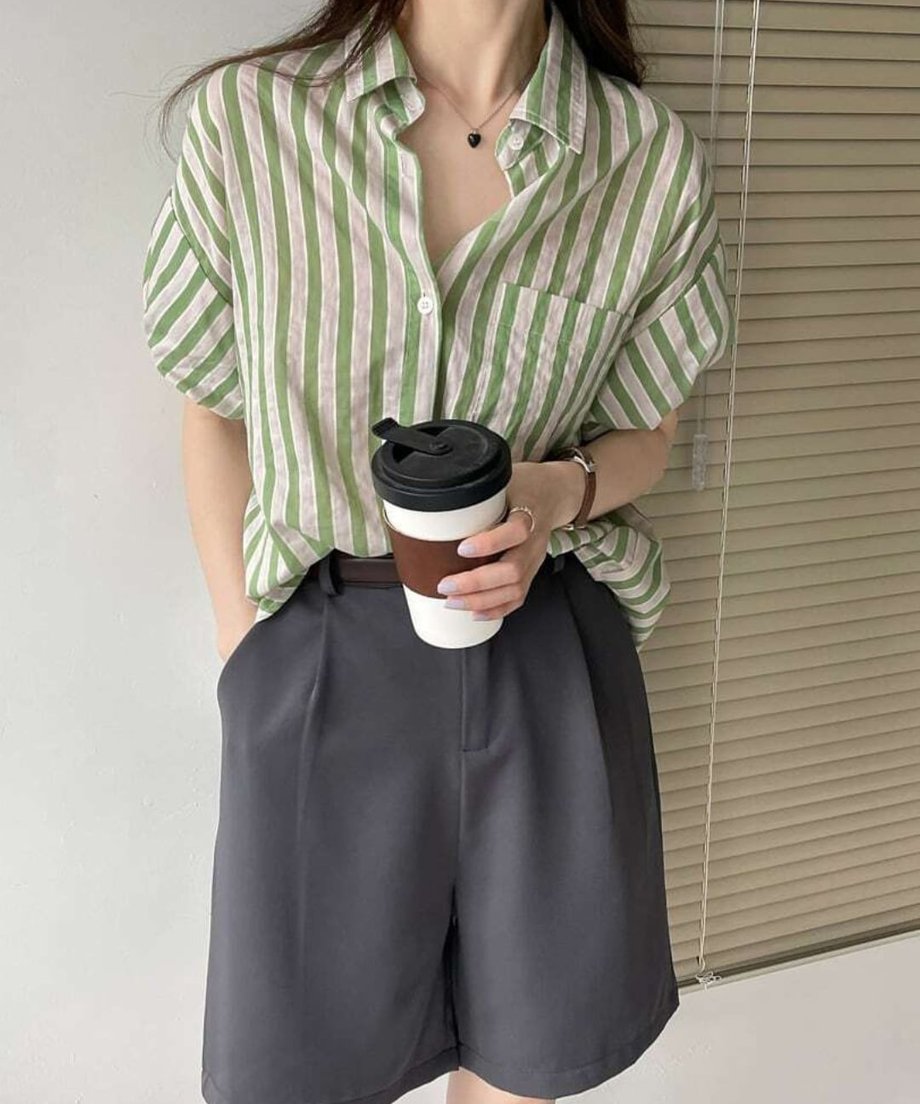 グリーンのストライプシャツをダークグレーのハーフパンツに合わせ、コーヒーを手にした都会的な夏コーデ。