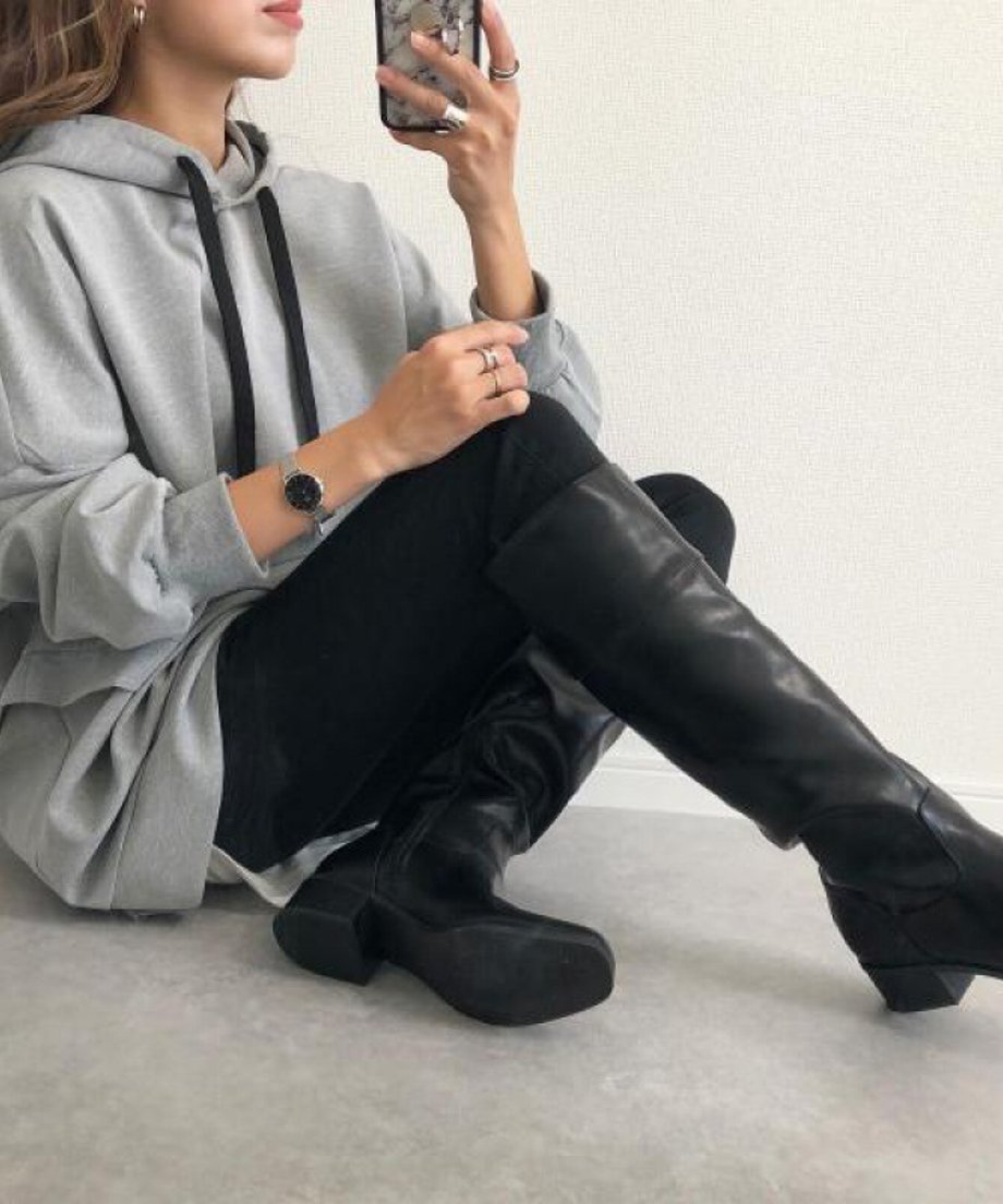 ：グレーのオーバーサイズフーディーを着用し、白のインナーを裾から見せ、黒のスキニーパンツを合わせた女性のバストアップ。