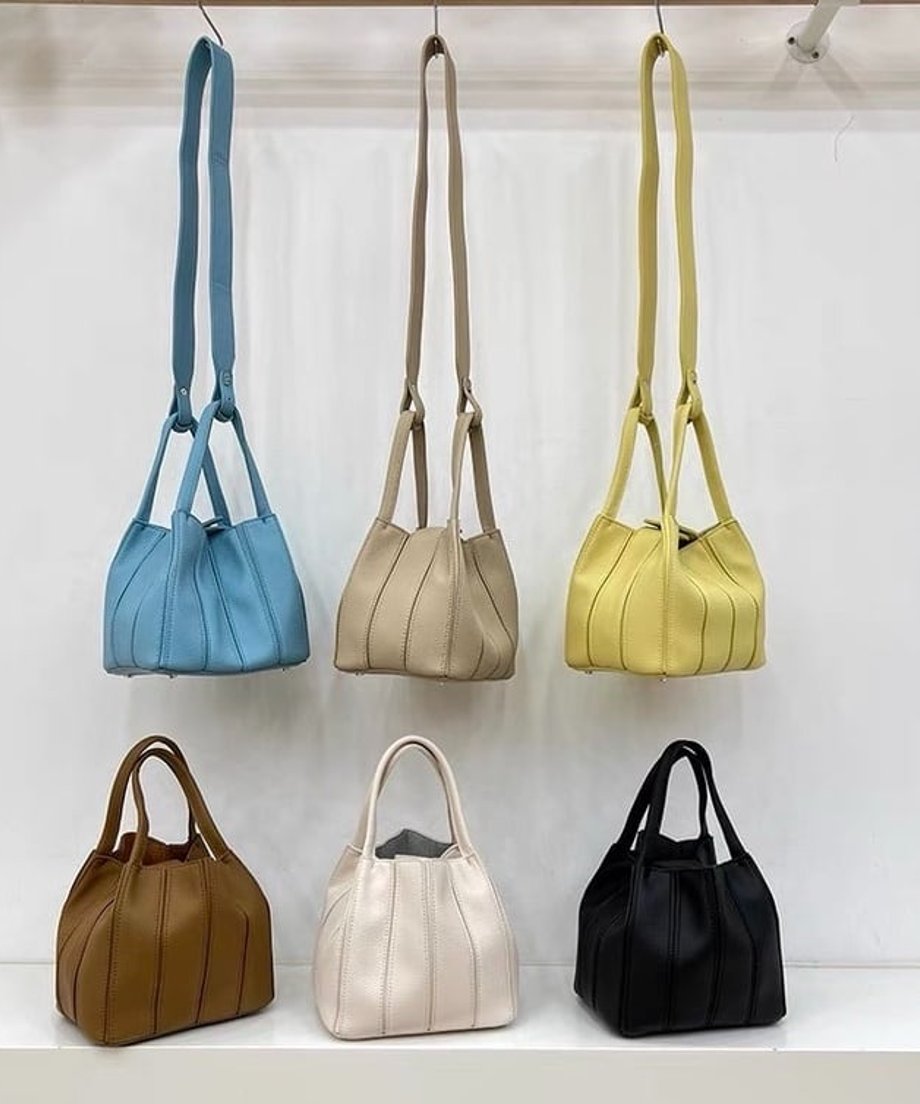 壁面に吊るされたロングショルダーストラップ付きの2WAYミニバッグ