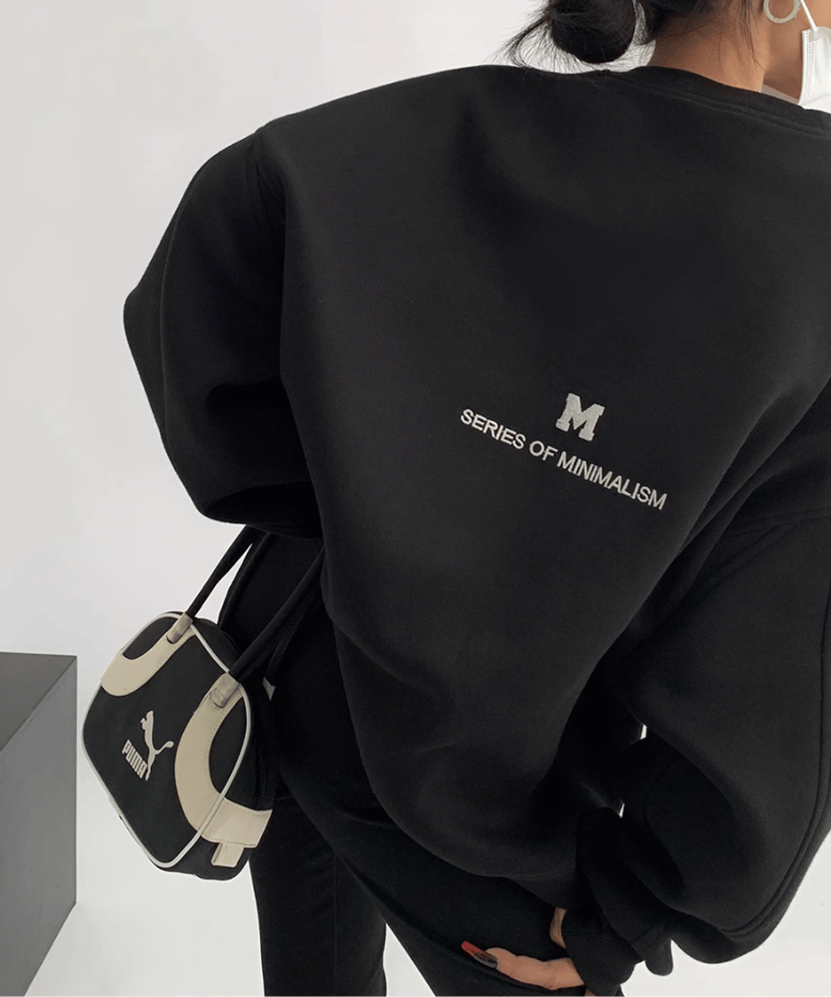 黒のオーバーサイズスウェットを着用した女性の背中側のショット。黒のスキニーとバックをコーディネートしている。