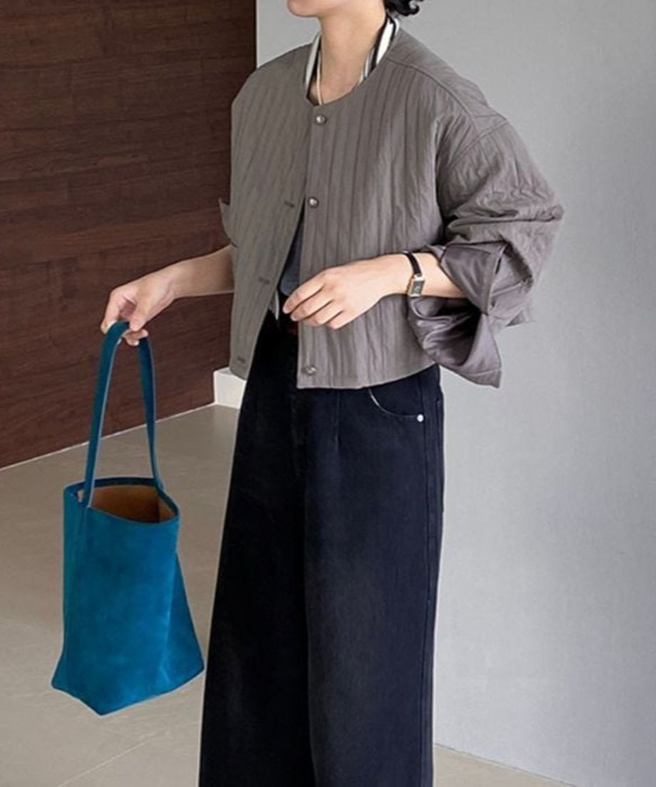 グレーのバルーンスリーブジャケットを着用した女性の全身。ジャケットはショート丈で、濃い色のワイドデニムパンツ、青いトートバッグを合わせたコーディネート。