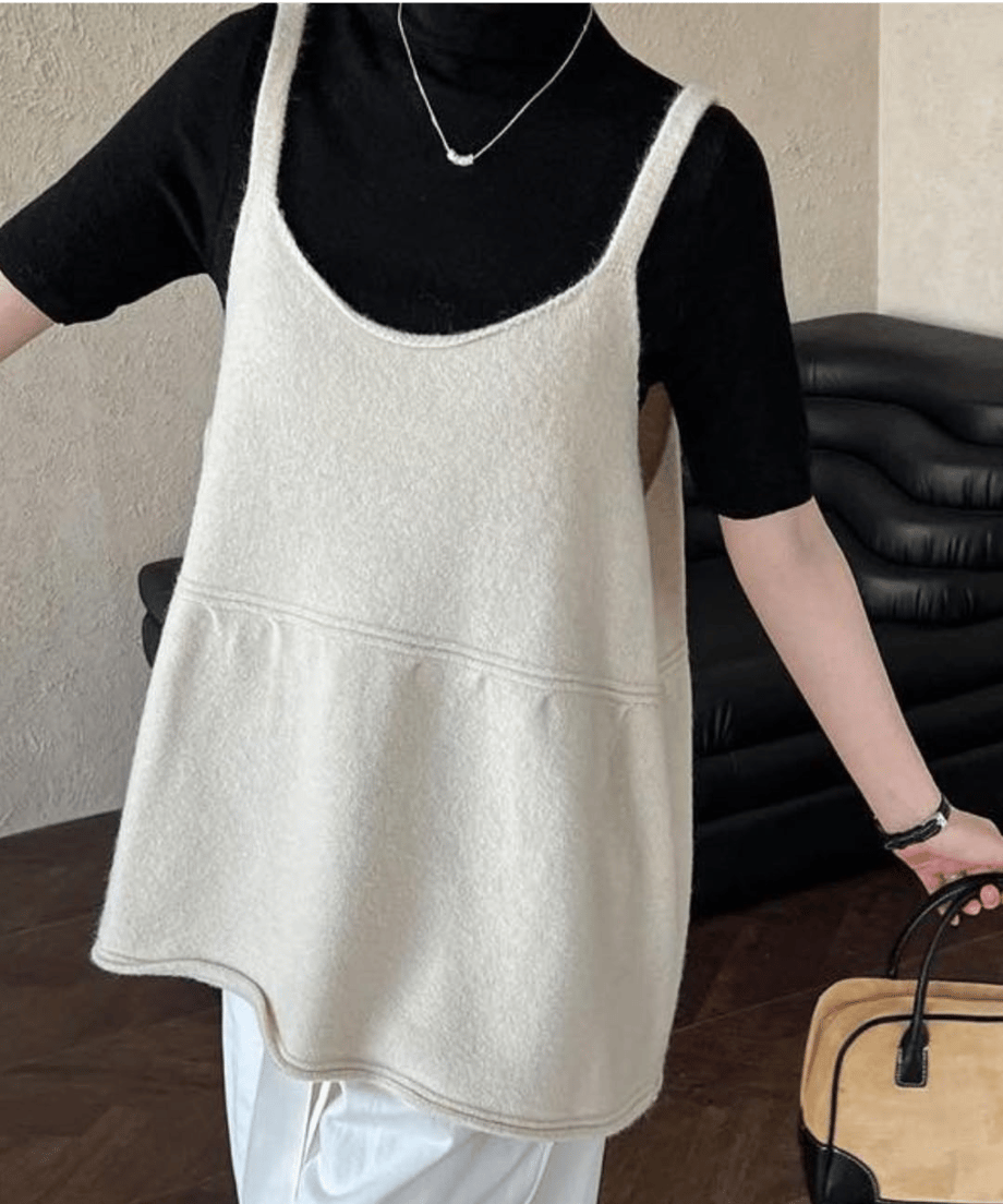 黒のハイネックカットソーにオフホワイトのウール混チュニックトップスを重ねた女性