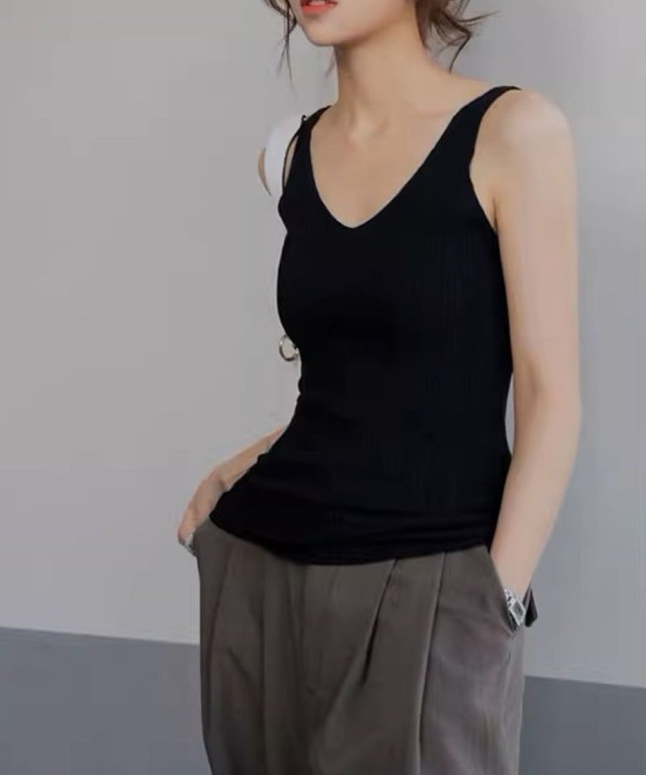 ブラックのリブタンクトップを着た女性がリラックスした姿勢で立っている画像。カジュアルスタイルに最適。