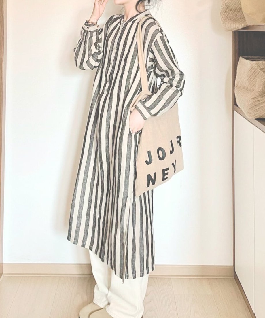 ベージュのトートバッグを手に持ち、リラックスした雰囲気で立つ女性。
