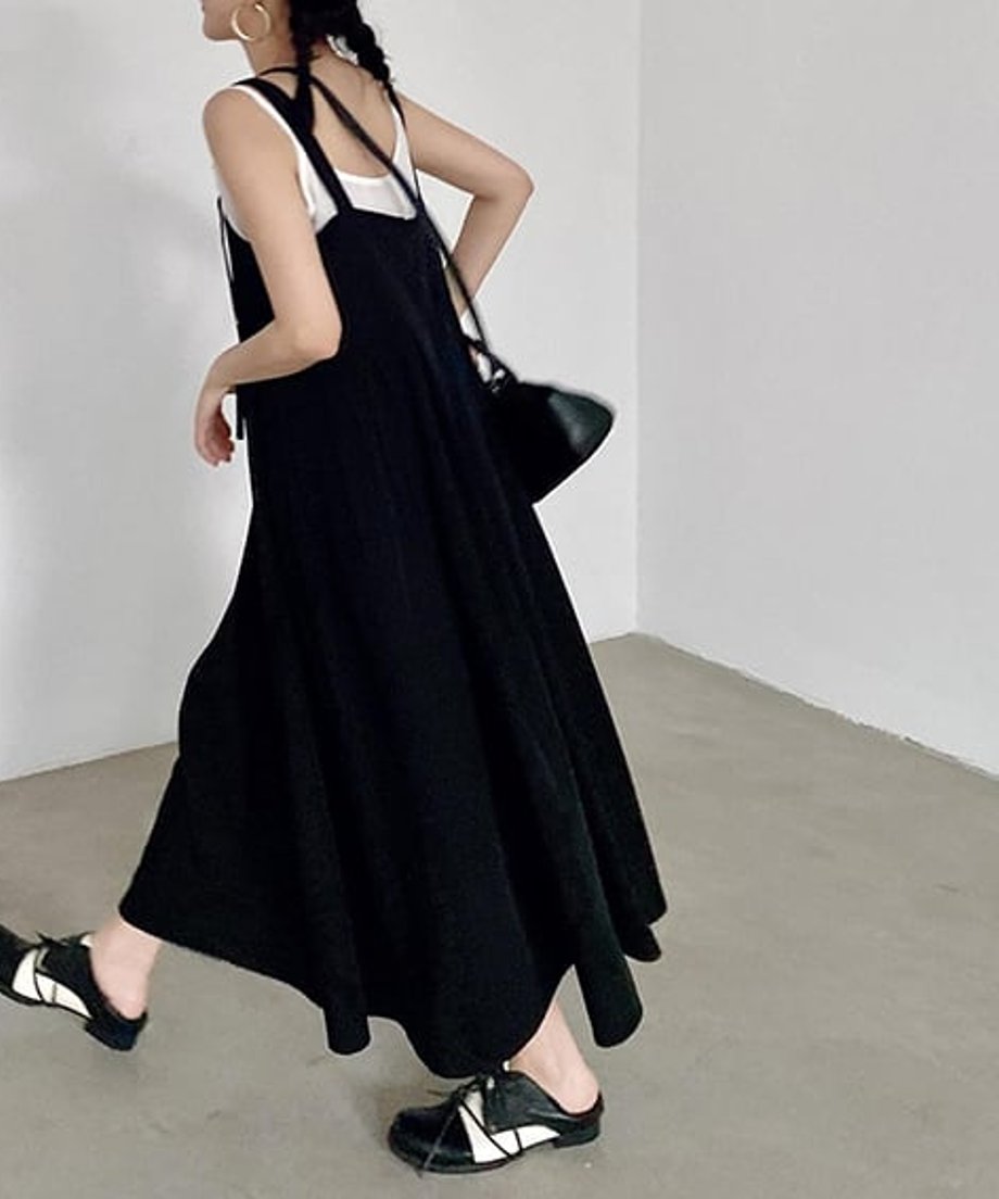黒のサスペンダーワンピースに白のタンクトップをインナーにした女性の背面ショット。