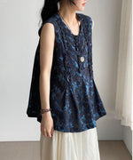 胸元にタックとフリルの入ったネイビー花柄ブラウスを着用した女性の上半身写真