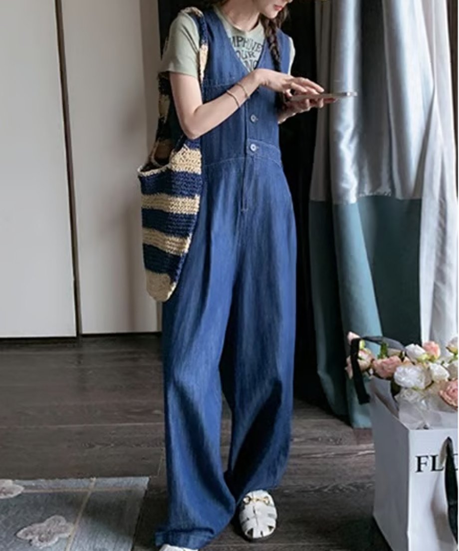 Vネックのデニムワイドレッグジャンプスーツの下に、薄いグリーンのTシャツを重ね着した女性の全身写真。