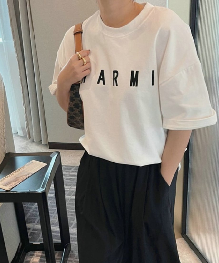 ホワイトのロゴTシャツにゴールドのリングを合わせ、CELINEのバッグを肩に掛けた上品なデイリースタイル。