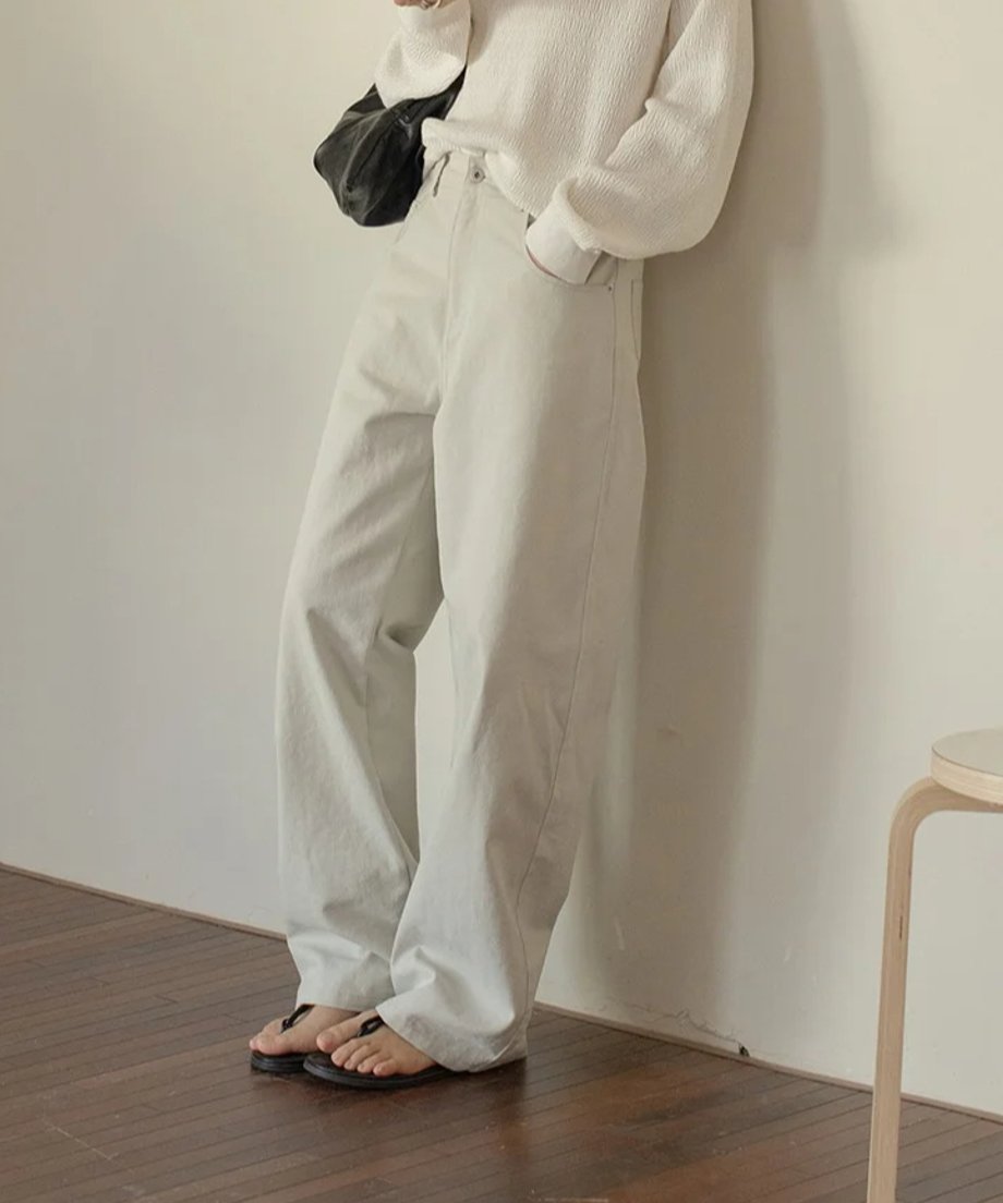 ライトグレーのワイドレッグパンツに白いセーターを合わせたコーディネート。