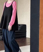 ピンクのインナーにブラックのチュニックトップスにデニムパンツをコーディネートした女性