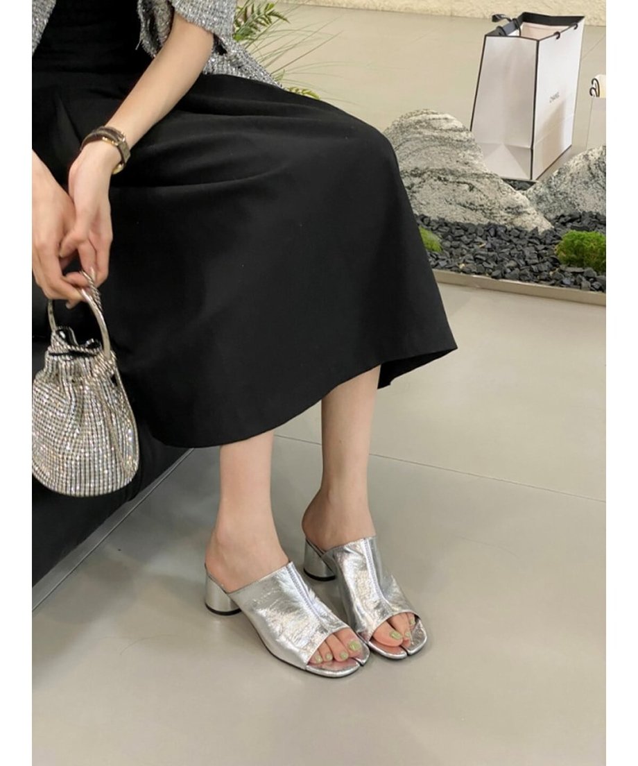 シルバーのミュールを着用した女性の座っている足元。