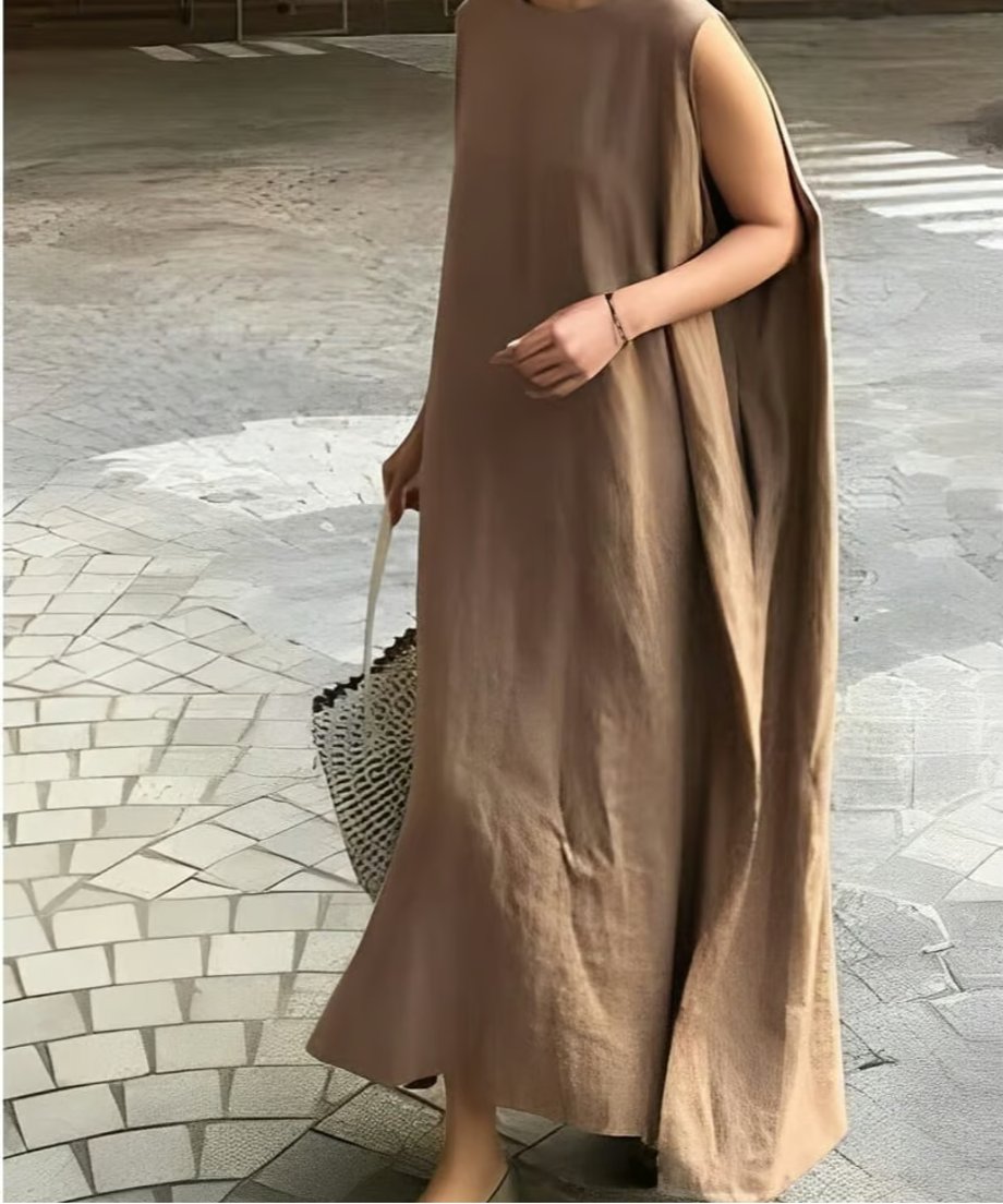 ブラウンのスリーブレスドレスを着用して屋外を歩く女性。トートバッグを合わせたカジュアルなコーディネート。
